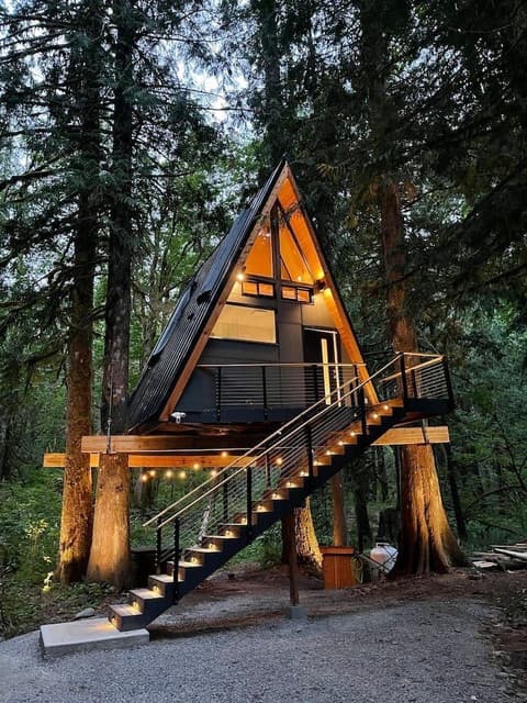 Chalé A-Frame construído, com fachada de vidro e deck de madeira